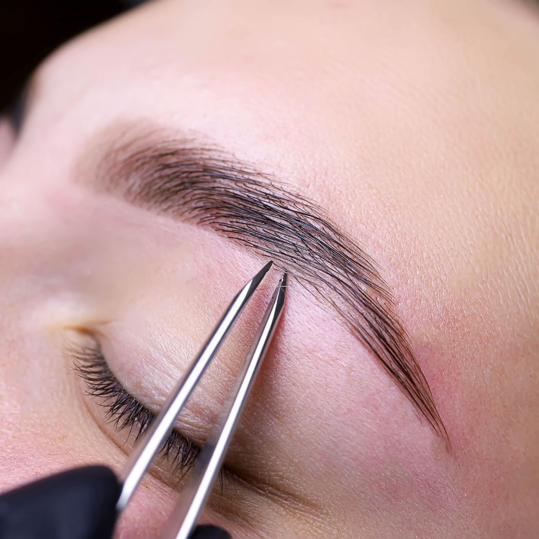 Augenbrauen-Styling bei Glamskin: die Augenbrauen einer Kundin werden mit einer Pinzette in Form gebracht.